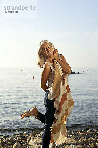 Glückliche Frau mit Schal am Strand