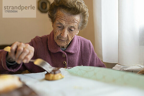Ältere Frau mit Cupcake sitzt am Esstisch