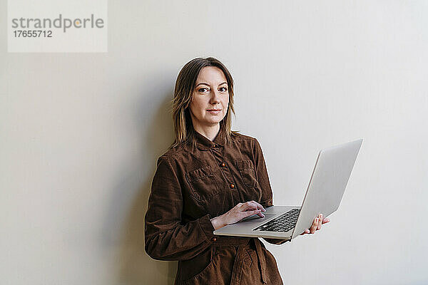 Frau hält Laptop vor weißem Hintergrund