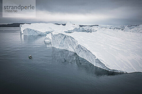 Kleines Boot  das aus der Luft vor extremen Eisbergen segelt
