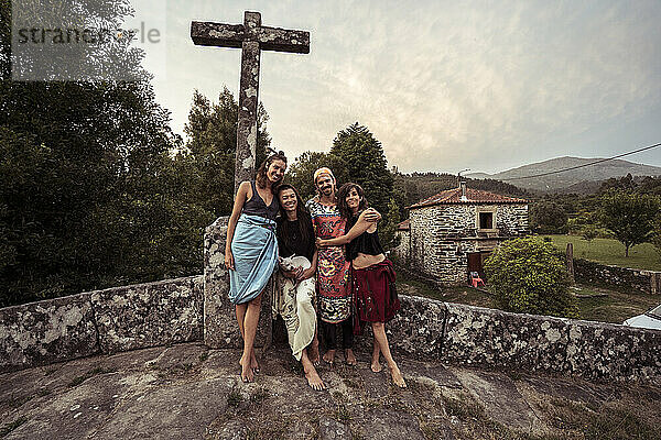 Vier Freunde und Liebende umarmen und lächeln auf einer steinernen Braut in Portugal