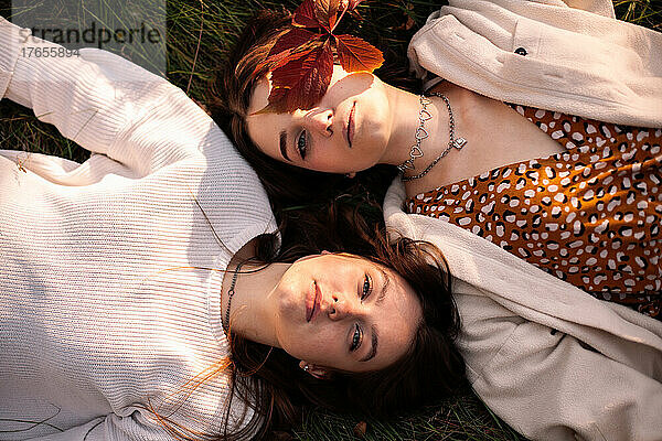 Blick von oben auf ein lesbisches Paar  das im Herbst auf Gras liegt
