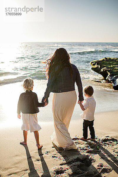 Mutter hält Händchen mit kleinen Kindern am Strand in San Diego