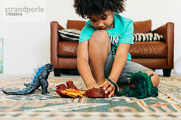 Kleiner Junge spielt mit seinen Spielsachen auf dem Wohnzimmerboden