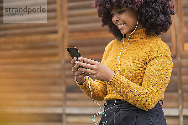 Junge Afro-Frau hört Musik auf ihrem Mobilgerät.