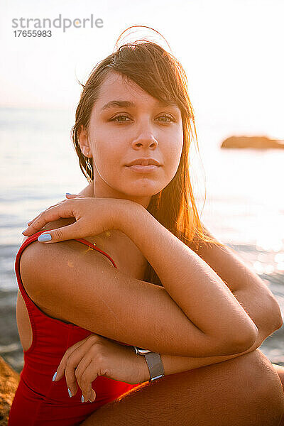 Porträt einer Frau im roten Badeanzug am Strand