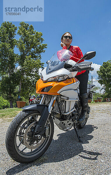 Thailänderin ruht sich auf ihrem Abenteuermotorrad in Nordthailand aus