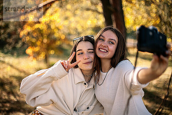 Fröhliche Freundinnen machen im Herbst ein Selfie im Park