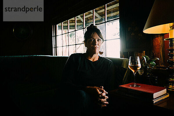 Frau sitzt in gemütlicher Hütte mit einem Glas Rose
