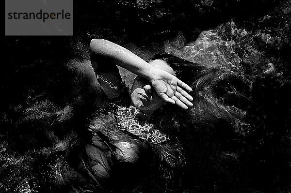 Mädchen liegt auf dem Wasser und bedeckt einen Teil ihres Gesichts mit der Hand
