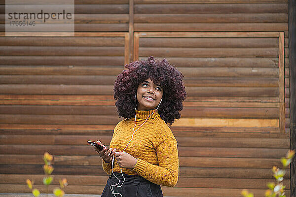 Junge Afro-Frau hört Musik auf ihrem Mobilgerät.