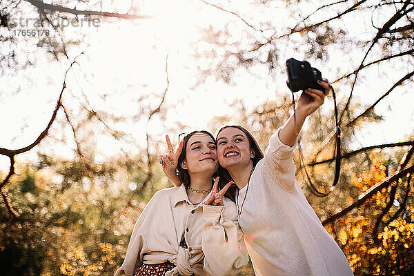 Glückliche Freundinnen machen im Herbst ein Selfie im Park