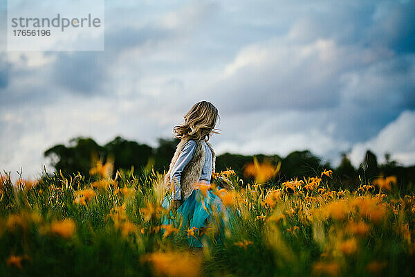 Mädchen mit blauem Himmel und orangefarbenen Blumenfeldern