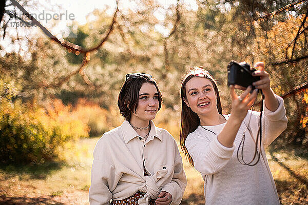 Fröhliche Freundinnen machen im Herbst ein Selfie im Park