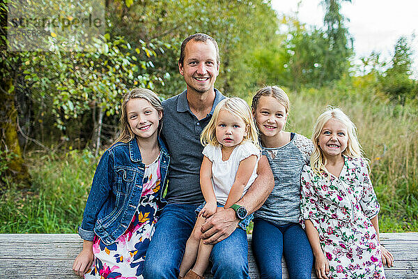 Porträt eines Vaters  der mit seinen vier schönen Töchtern sitzt.