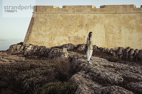 Androgyne Person steht vor historischer Festung in Portugal