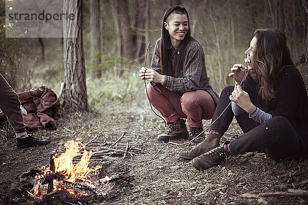 lächelnde androgyne Frauen  die Marshmallows essen