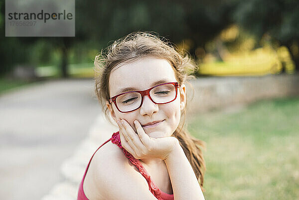 Porträt einer lächelnden Teenagerin mit Brille und geschlossenen Augen