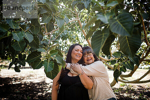 Mutter umarmt Tochter im von Bäumen umgebenen Park in San Diego