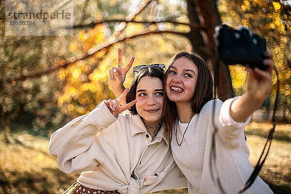 Fröhliche Mädchen im Teenageralter machen im Herbst ein Selfie im Park