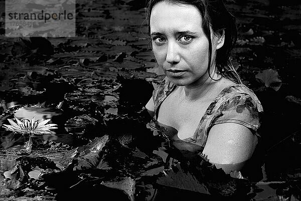 dramatisches Porträt eines Mädchens in einem See mit Lotusblumen