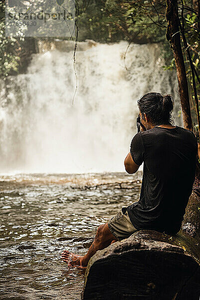 Mann macht professionelles Foto eines Wasserfalls