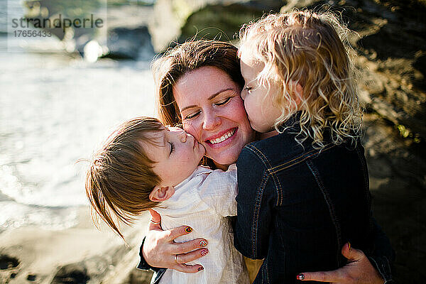 Mutter bekommt am Strand von San Diego Küsse von Kindern