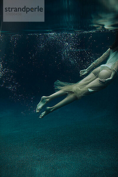 Eine junge Frau schwimmt an einem trüben Tag unter Wasser