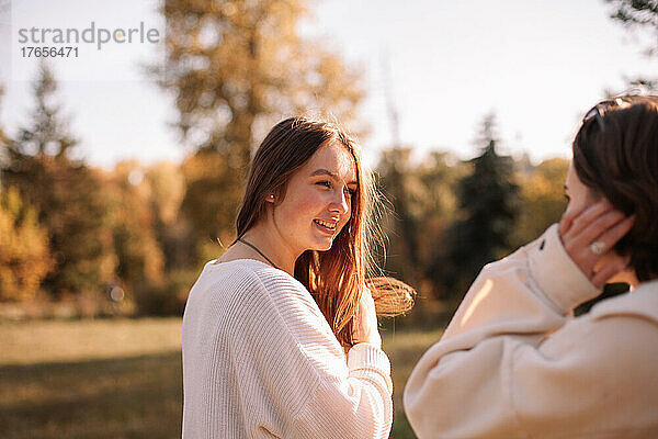 Glückliche junge Frau schaut ihre Freundin an  während sie im Park steht