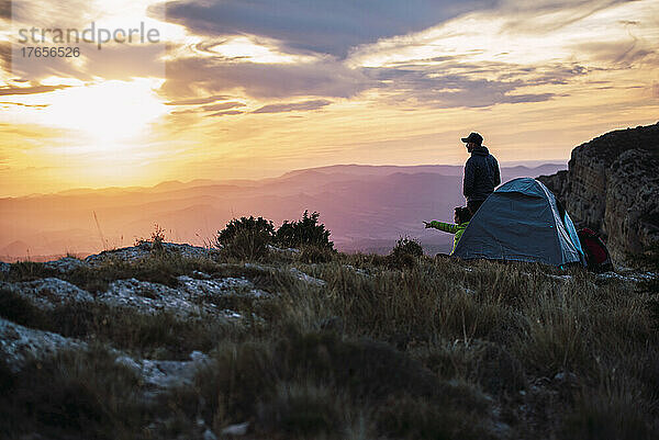 Paar campt in den Bergen und genießt den Sonnenuntergang.
