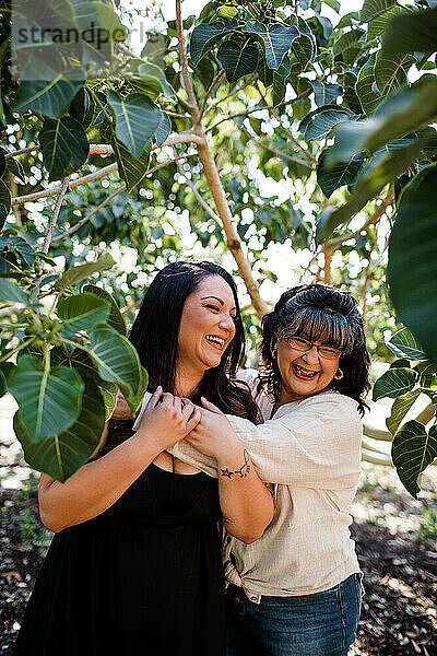 Mutter und Tochter lachen  umgeben von Bäumen in San Diego