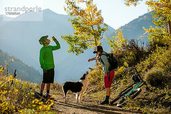 Ein Paar genießt im Herbst eine Mountainbiketour mit seinem Hund