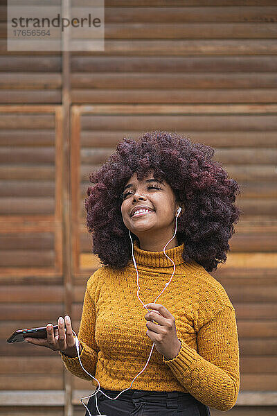 Junge Afro-Frau hört Musik auf ihrem Mobilgerät.