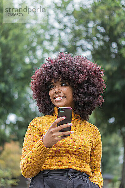 Junge Afro-Frau schreibt SMS auf ihrem Handy.