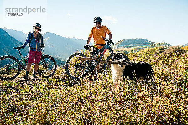 Ein Paar genießt im Herbst eine Mountainbiketour mit seinem Hund