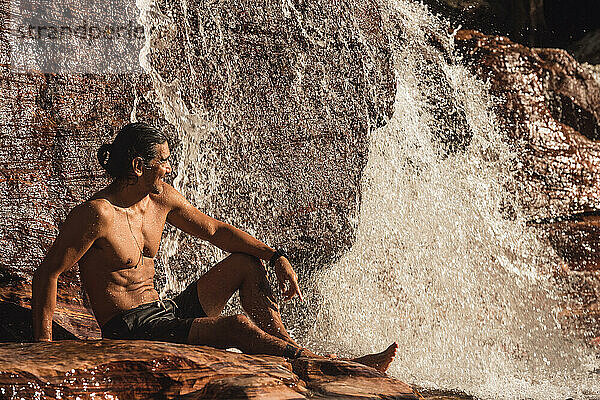 Mann lacht beim Baden im Wasserfall