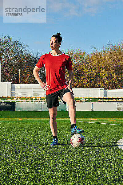 Eine Fußballspielerin posiert mit einem Fußball