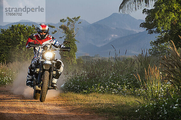 Mann fährt mit seinem Scrambler-Motorrad in Nordthailand