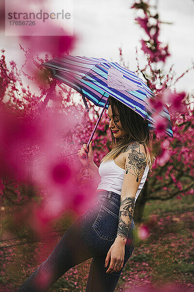 Hübsches tätowiertes Mädchen mit Regenschirm an einem bewölkten Tag