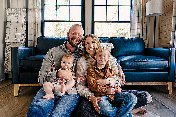 Eine vierköpfige Familie lächelt in die Kamera  während sie an einem sonnigen Tag in der Hütte sitzt