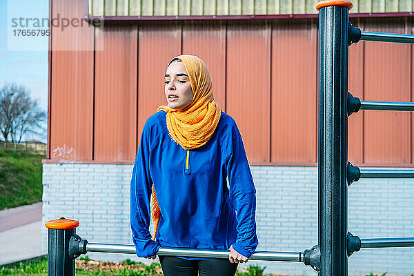 Arabische Frau trainiert an der Bar auf dem Sportplatz