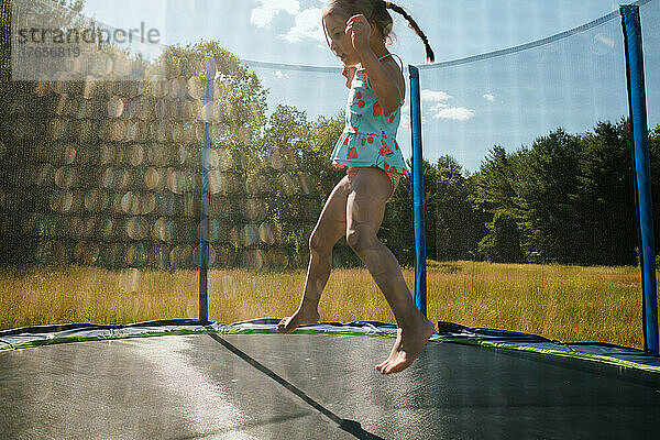 Junges Mädchen springt im Sommer auf Trampolin