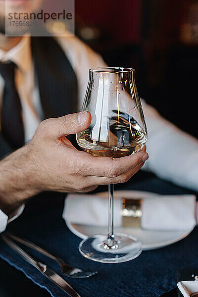 Glas mit Wein in der Hand des Bräutigams