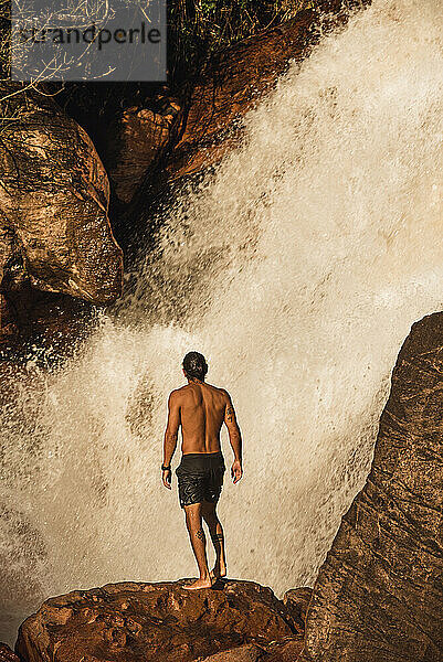 Gesunder Mann klettert auf Felsen an einem Wasserfall