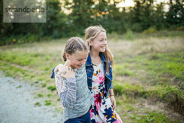 Zwei fröhliche Mädchen lachen  lächeln  spielen draußen.