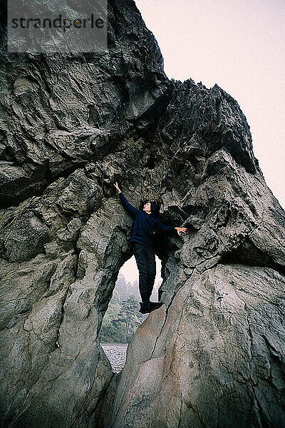 Vermummter Teenager klettert Felsklippe im Olympic-Nationalpark