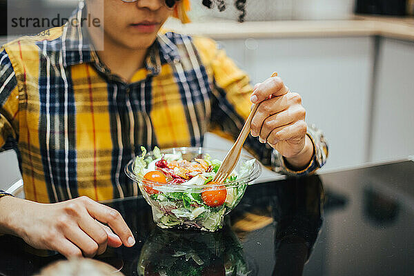 Junger Afroamerikaner  der bequem zu Hause Salat isst