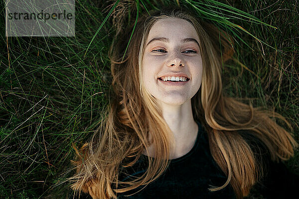 Glückliche Frau  die lächelnd auf dem Gras liegt