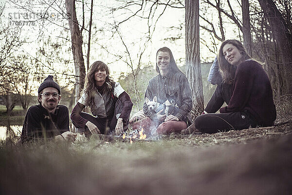 Alternative Freunde sitzen mit kleinen Hunden am Lagerfeuer