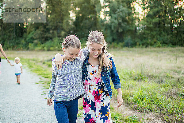 Junge Mädchen lächeln  lachen und spielen im Park  die Arme um die Arme gelegt.